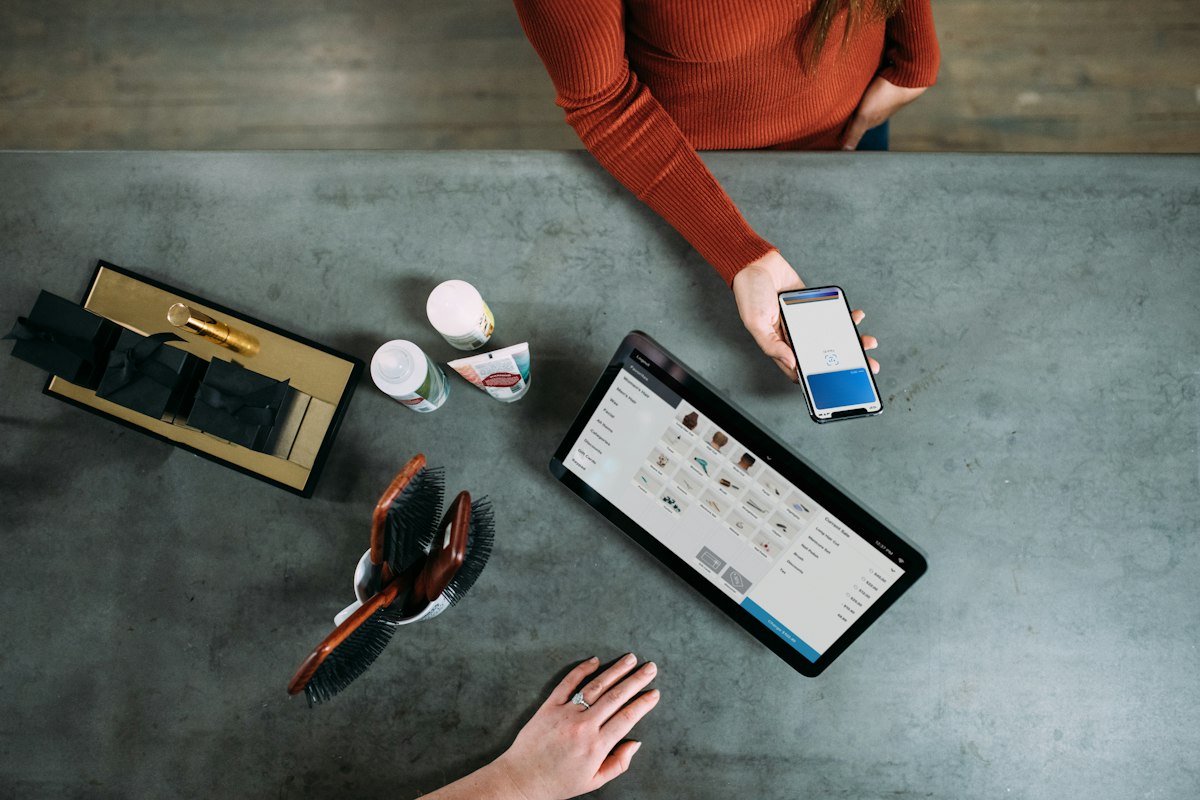 Client présentant son téléphone au comptoir d'un commerce équipé d'une caisse tablette
